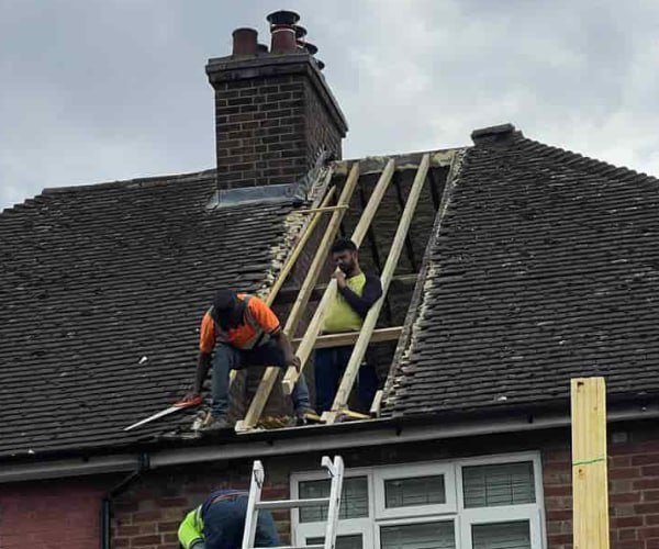 This is a photo of a roof repair being carried out. A section of the roof has been stripped and two roofers are replacing the rafters. Works being carried out by LKP Roofing Thorne